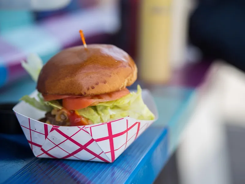 Burger im Papiertablett am Ausgabefenster eines Foodtrucks Burger im Papiertablett am Ausgabefenster eines Foodtrucks